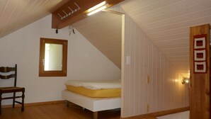 Une chambre à coucher avec un lit, une chaise, une fenêtre et un plafond en bois.