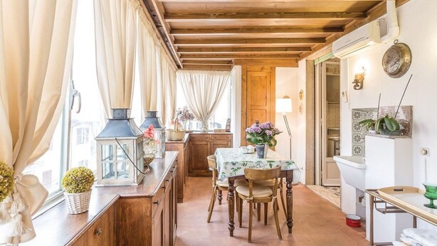 Una cocina acogedora con armarios de madera, una mesa de comedor con sillas y una ventana con cortinas.