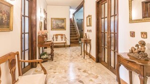 Un pasillo con suelo de baldosas, muebles de madera y una escalera al fondo.