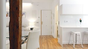 Een moderne woonkamer met een houten accentmuur, witte meubels en een glazen salontafel.