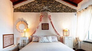 A bedroom with a stone ceiling, a canopy bed, a stone wall, a mirror, and a radiator.