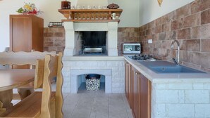 A kitchen with a stone fireplace, a microwave, and a sink.