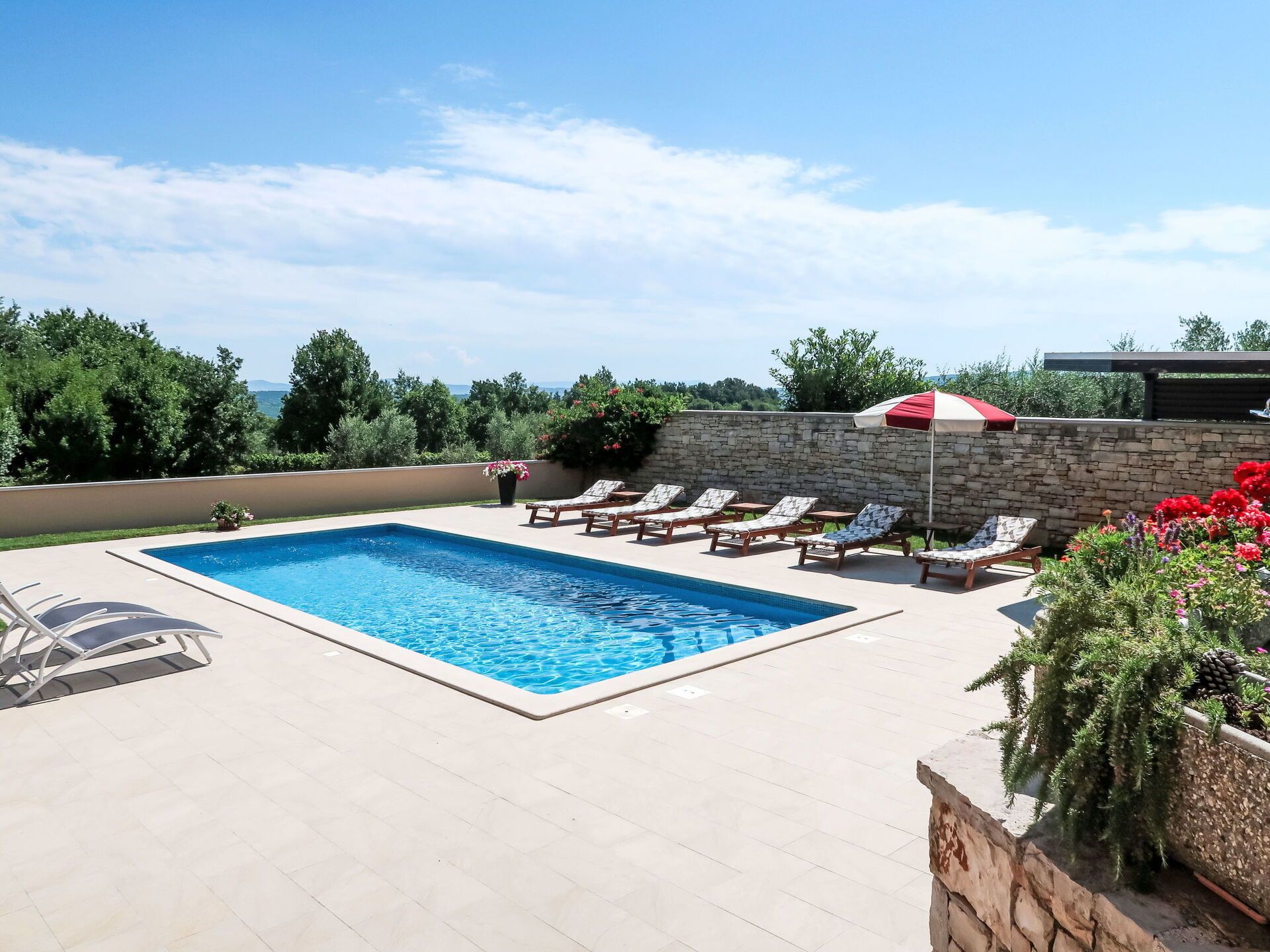 A swimming pool with lounge chairs and a stone wall.