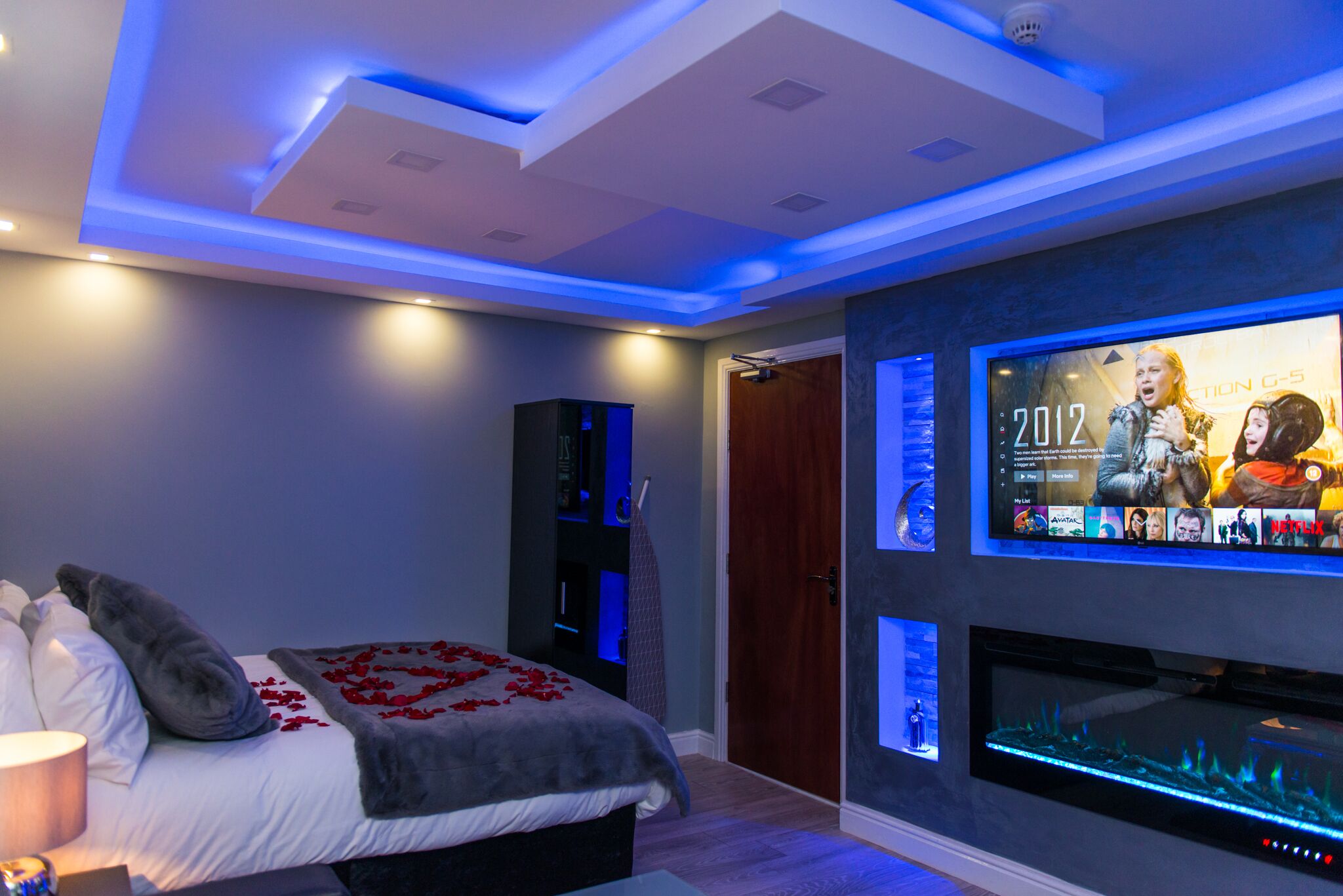 Ein modernes Schlafzimmer mit einem Bett, einem an der Wand befestigten Fernseher und einem eingebauten Aquarium.