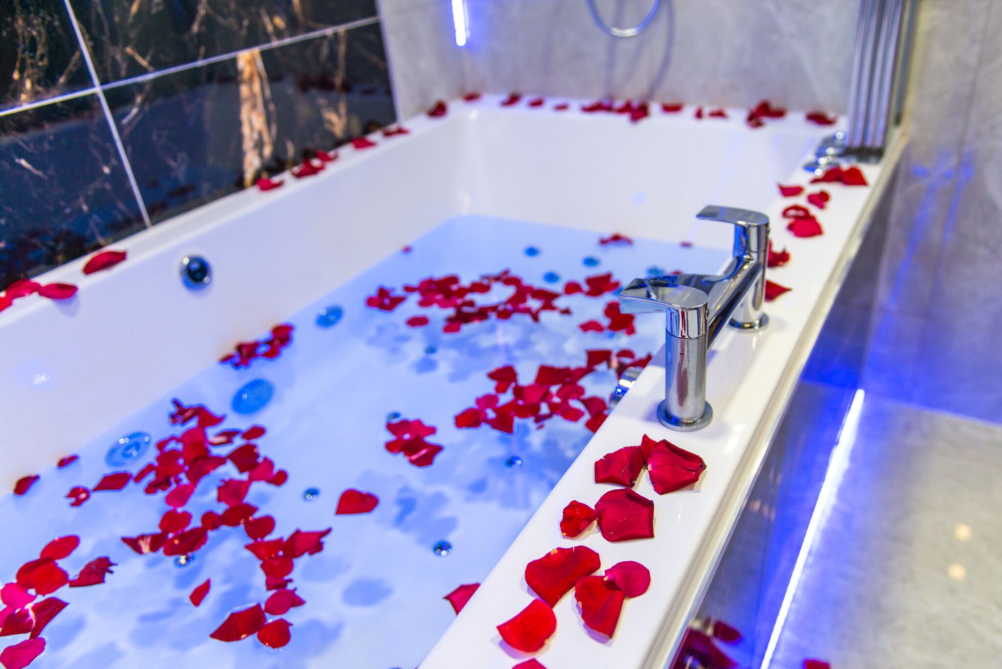 A bathtub filled with water and rose petals.
