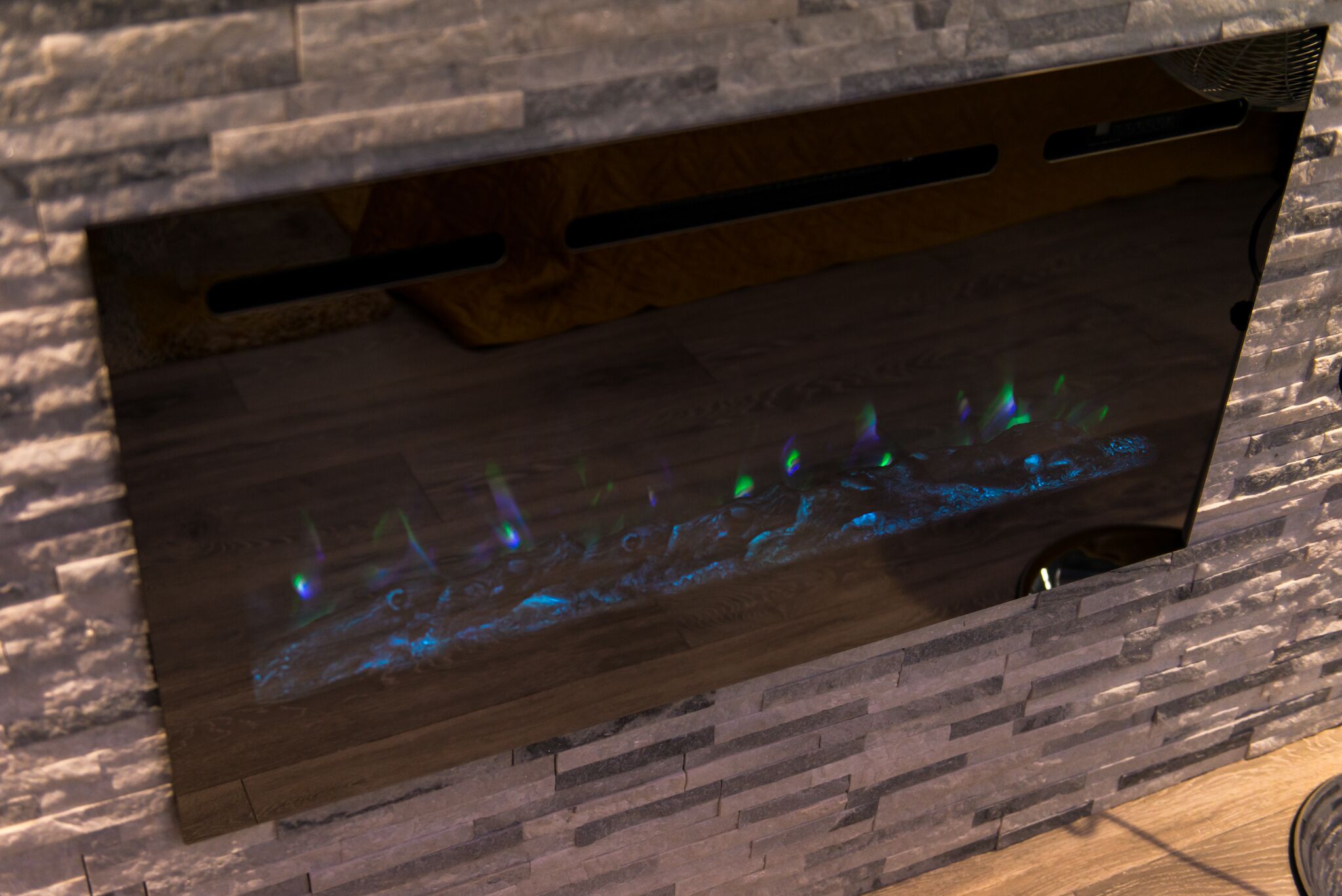 Pareti in legno con camino integrato che emana luci blu e verdi.