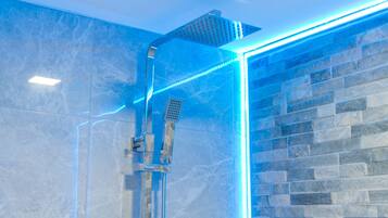 Una ducha moderna con mampara de vidrio e iluminación LED azul.