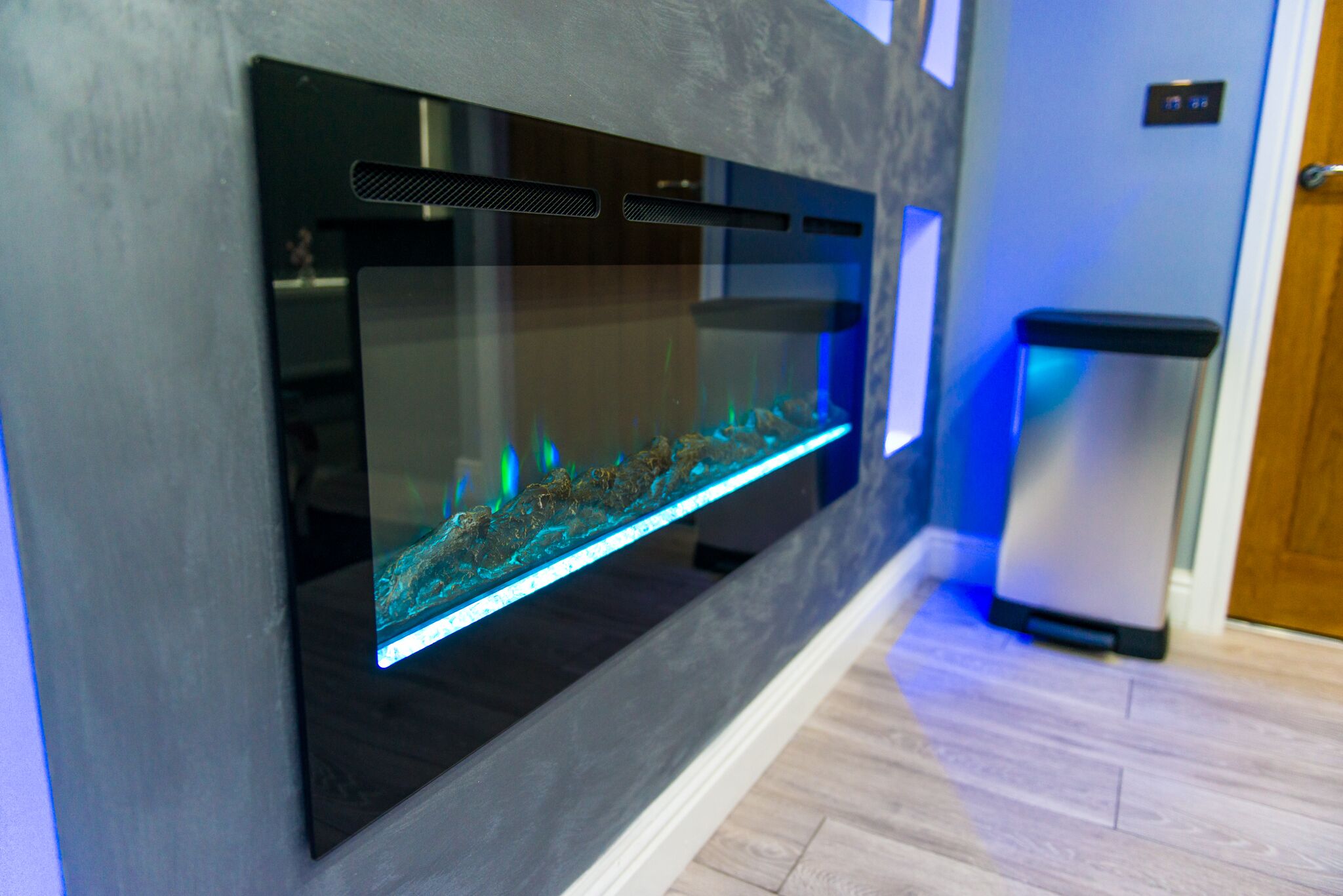 Una cucina moderna con un acquario integrato, un frigorifero in acciaio inossidabile e un pavimento in legno.