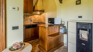 A compact kitchen with a stone backsplash, wooden cabinetry, a built-in dishwasher, and a small island with a microwave. - Beautiful private villa for 2 people with WIFI, A/C, TV, patio, pets allowed and panoramic view (Roccastrada)