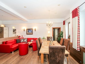 Una sala de estar moderna con un sofá rojo, una mesa de comedor de madera y una araña.