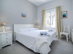 Une chambre à coucher avec un lit, des tables de chevet, une chaise et une fenêtre avec des rideaux.