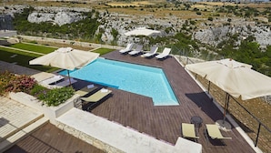 A swimming pool with sun loungers and umbrellas, surrounded by a landscaped garden with a view of rocky hills. - Stunning private villa for 16 people with WIFI, hot tub, private pool, A/C, TV and patio (Modica)