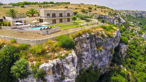 A stone building with a pool and outdoor seating, surrounded by a cliffside landscape. - Stunning private villa for 16 people with WIFI, hot tub, private pool, A/C, TV and patio (Modica)