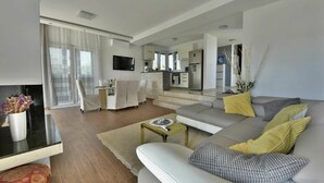 En moderne stue med sofa, sofabord og et spiseområde med stole.