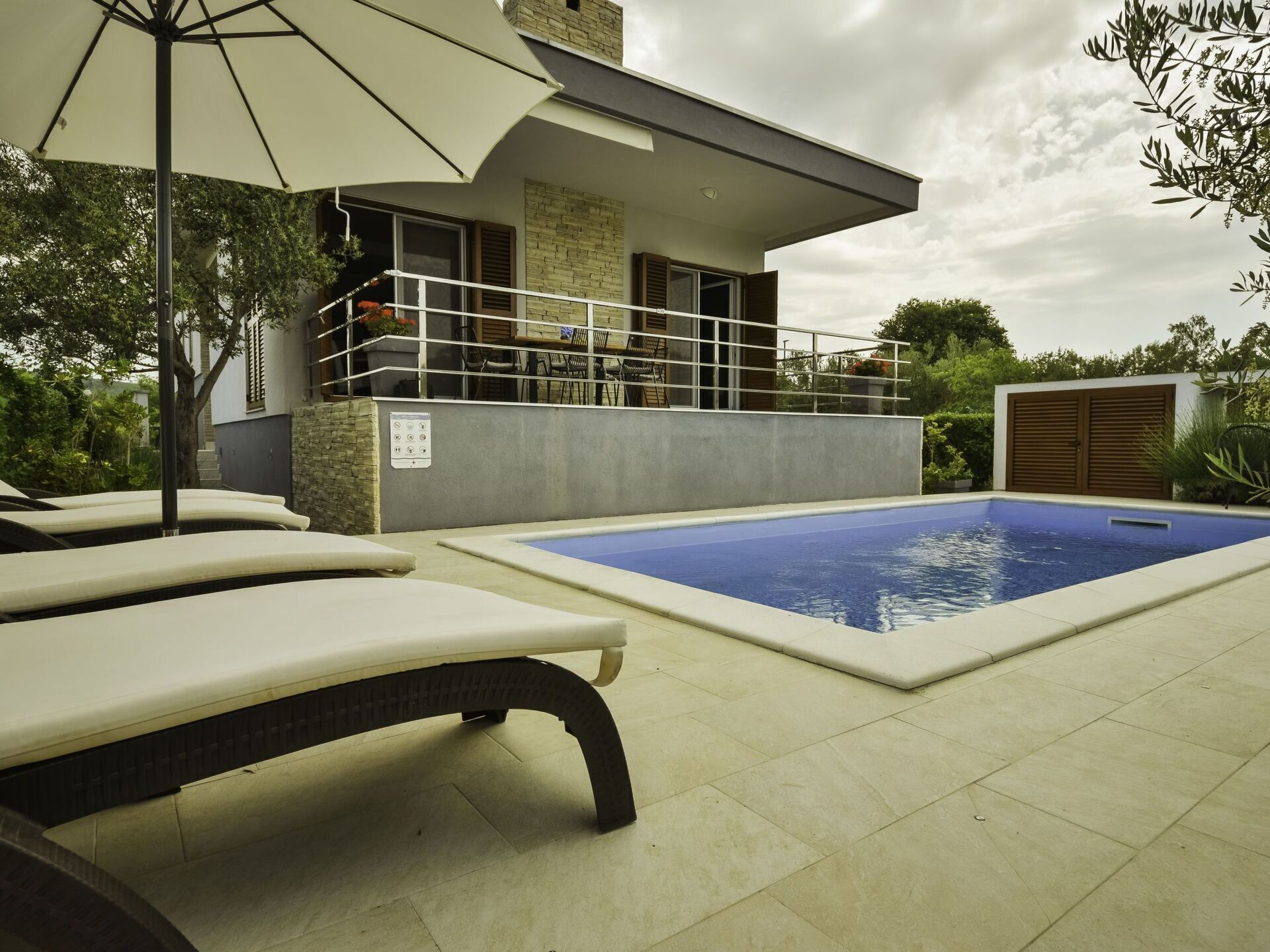 Una casa moderna con piscina, mobiliario exterior y zona de patio cubierta.