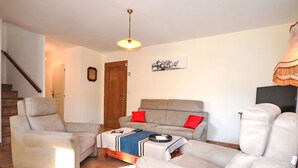 Un salon comprenant un canapé, deux fauteuils, une table basse et un téléviseur.