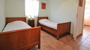 Une pièce avec deux lits en bois, une table de chevet avec des lampes, une fenêtre avec des rideaux et une porte.