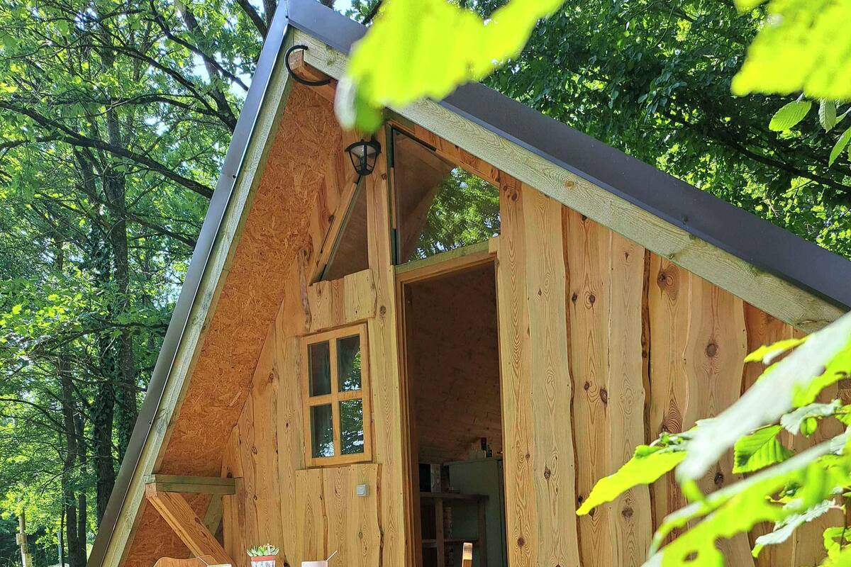 A wooden cabin with a dining table and chairs outside.