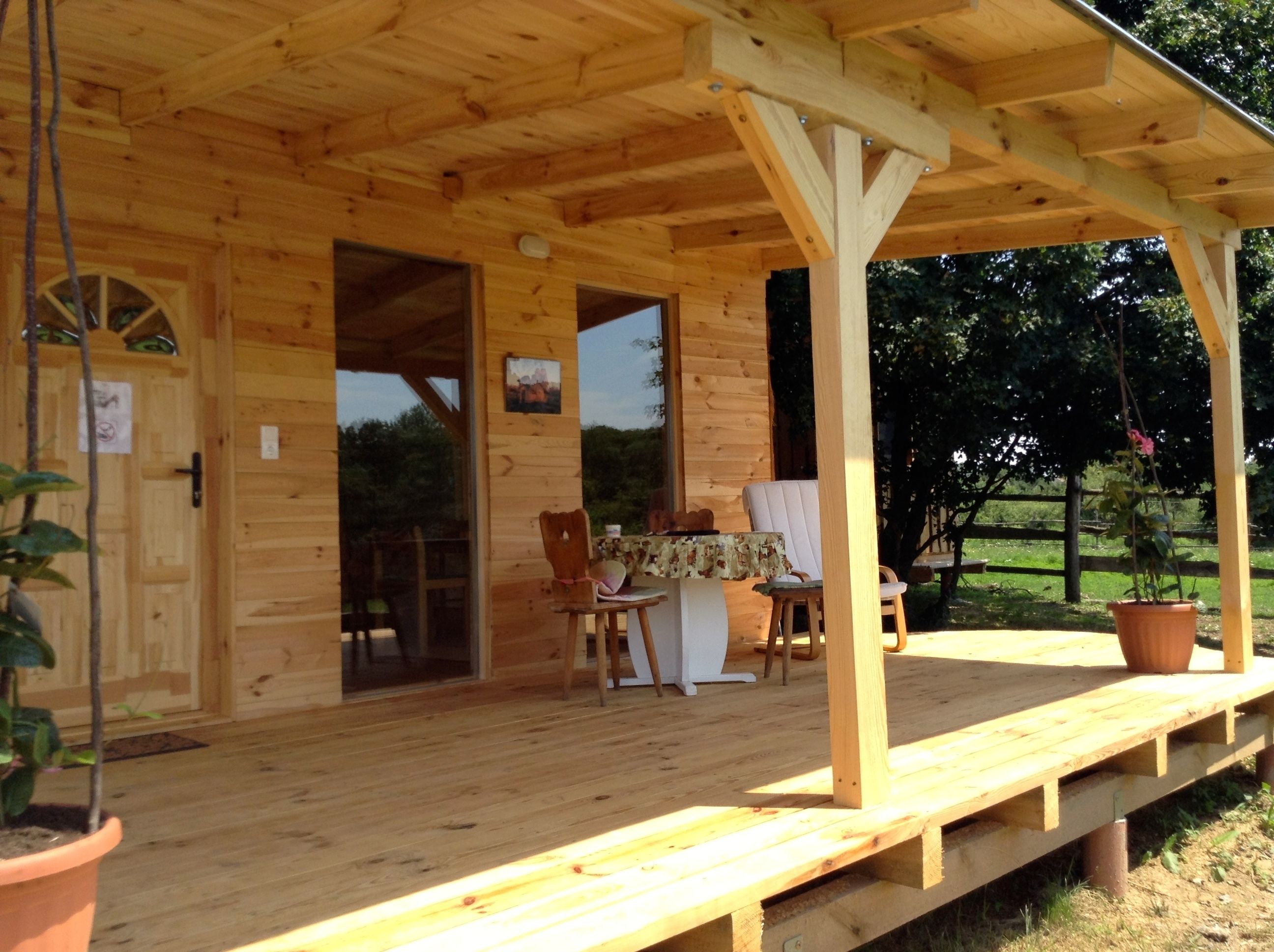 Eine Holzhütte mit Veranda, einem Esstisch und Stühlen.