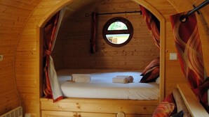 A cozy wooden cabin with a single bed, a window, and curtains. - Kerca Bio Farm (Kercaszomor)