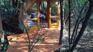 A wooden deck with a table and chairs, surrounded by trees. - Kerca Bio Farm (Kercaszomor)