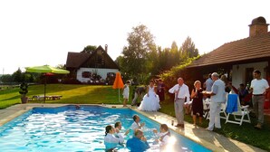 A swimming pool with people around it, a house in the background, and a grassy area. - Kerca Bio Farm (Kercaszomor)
