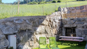 A stone wall with two green chairs and a bench outside. - Beautiful apartment for 6 people with WIFI, TV, patio and panoramic view (Mitterdorf)