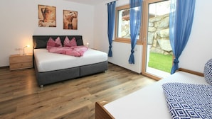 A bedroom with a bed, a bedside table, a nightstand, a window with curtains, and a view of the outside. - Beautiful apartment for 6 people with WIFI, TV, patio and panoramic view (Mitterdorf)