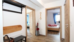 A bedroom with a wooden bed, a bedside table, a mirror, and a window with blue curtains. - Beautiful apartment for 6 people with WIFI, TV, patio and panoramic view (Mitterdorf)
