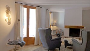 A living room with two grey armchairs, a small round table with candles, a floor lamp, and a fireplace. - Nice apartment for 6 guests with WIFI, TV, balcony, pets allowed and panoramic view (Celerina)