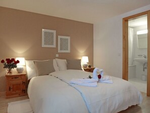 A neatly made bed with white linens, two bedside tables with lamps, a wooden nightstand, and a wall with two framed pictures. - Cosy apartment for 6 people with WIFI, TV, balcony, pets allowed and panoramic view (Celerina)