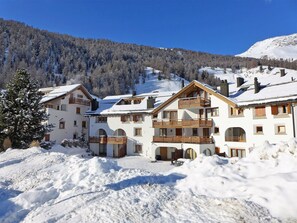 A multi-story hotel with balconies and a snow-covered landscape. - Cosy apartment for 6 people with WIFI, TV, balcony, pets allowed and panoramic view (Celerina)