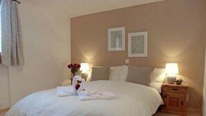 A neatly made bed with white linens, a pair of towels shaped like swans, and a vase with red flowers on a bedside table. - Nice apartment for 6 guests with WIFI, TV, balcony, pets allowed and panoramic view (Celerina)