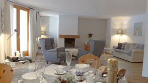 A modern living room with a fireplace, two armchairs, a sofa, and a dining table set for a meal. - Nice apartment for 6 guests with WIFI, TV, balcony, pets allowed and panoramic view (Celerina)