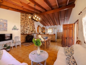 Uma sala de estar acolhedora com lareira, canto de jantar e cozinha.