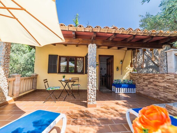 Une terrasse avec une table et des chaises, un petit jardin et une piscine.