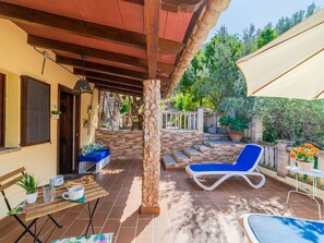 Uma área externa coberta com piscina, cadeiras de lounge e uma mesa com copos e um laptop.