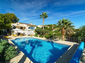 A swimming pool with lounge chairs, a palm tree, and a house with a tiled roof. - Wonderful private villa for 4 guests with private pool, A/C, WIFI, TV, terrace and panoramic view (Teulada)