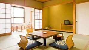 Una habitació japonesa tradicional amb fons de tatami, una taula baixa i coixins.