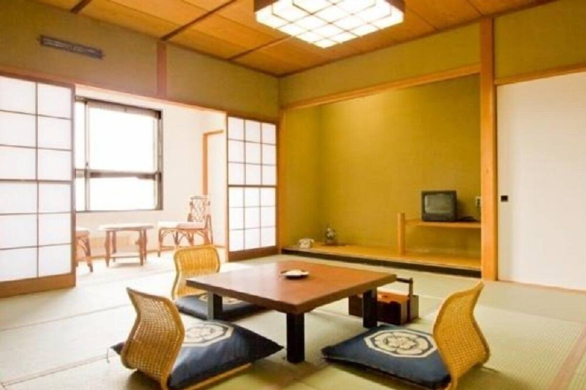 Une pièce de style japonais traditionnel, avec un sol recouvert de tatamis, une table basse et des coussins.