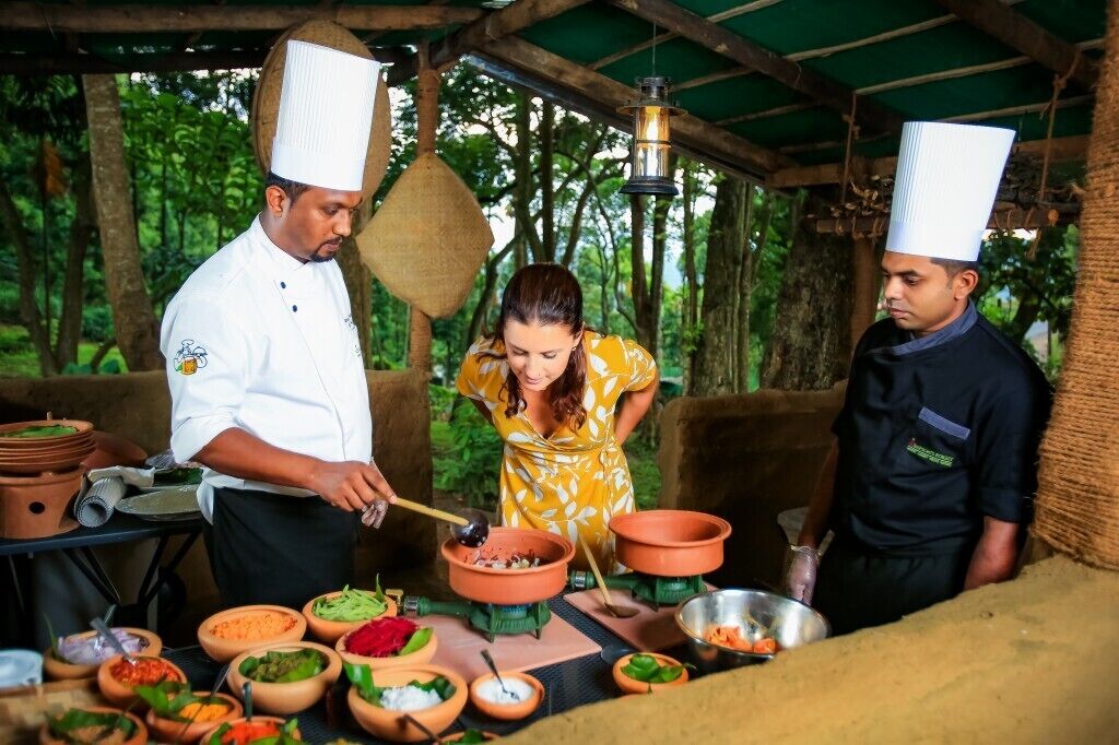 Un cocinero preparando comida al aire libre, con distintos utensilios de cocina e ingredientes a la vista.