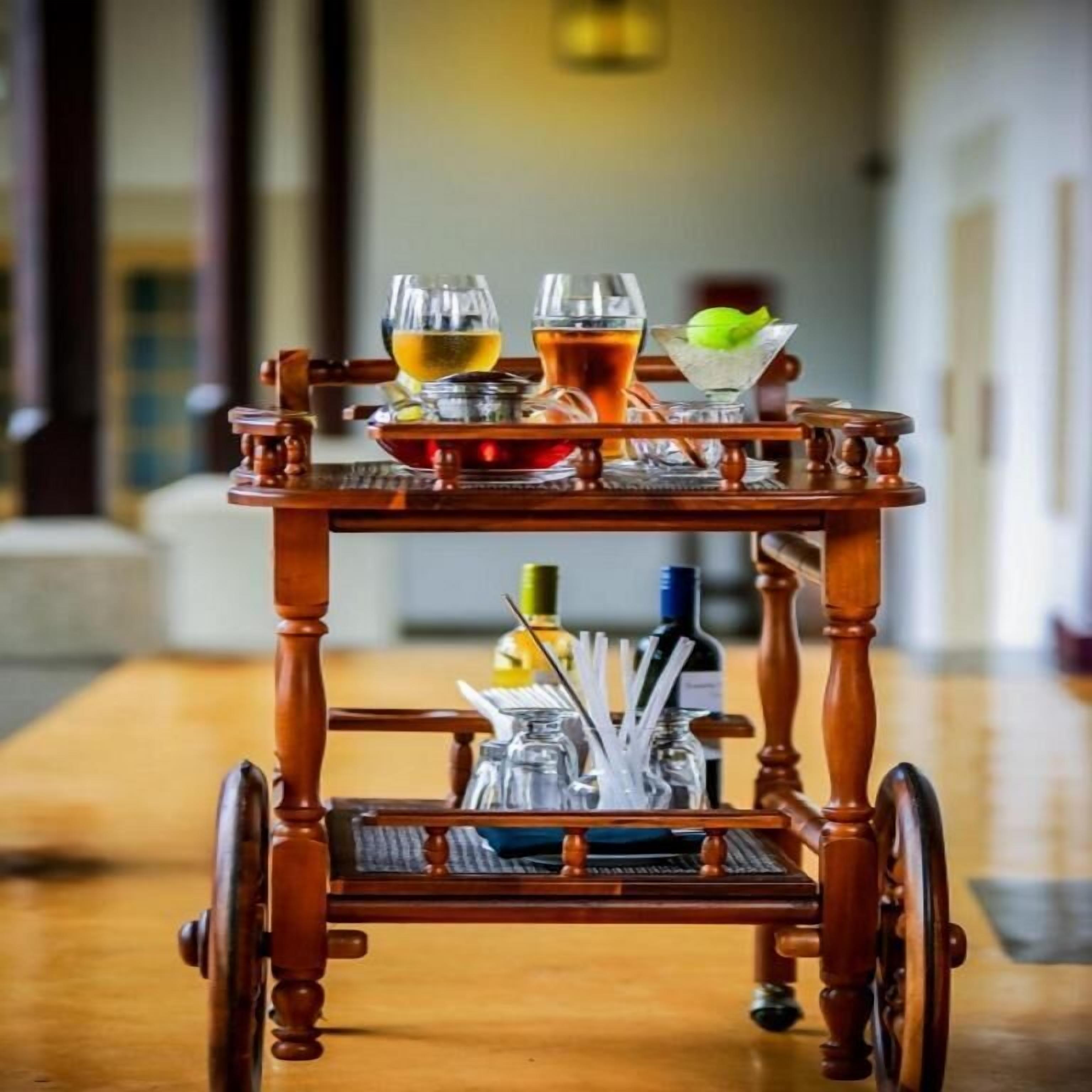 A wooden trolley with a tray table, glasses, and bottles, likely for serving drinks.