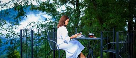 Una persona sentada a una mesa al aire libre con vistas a un paisaje montañoso.