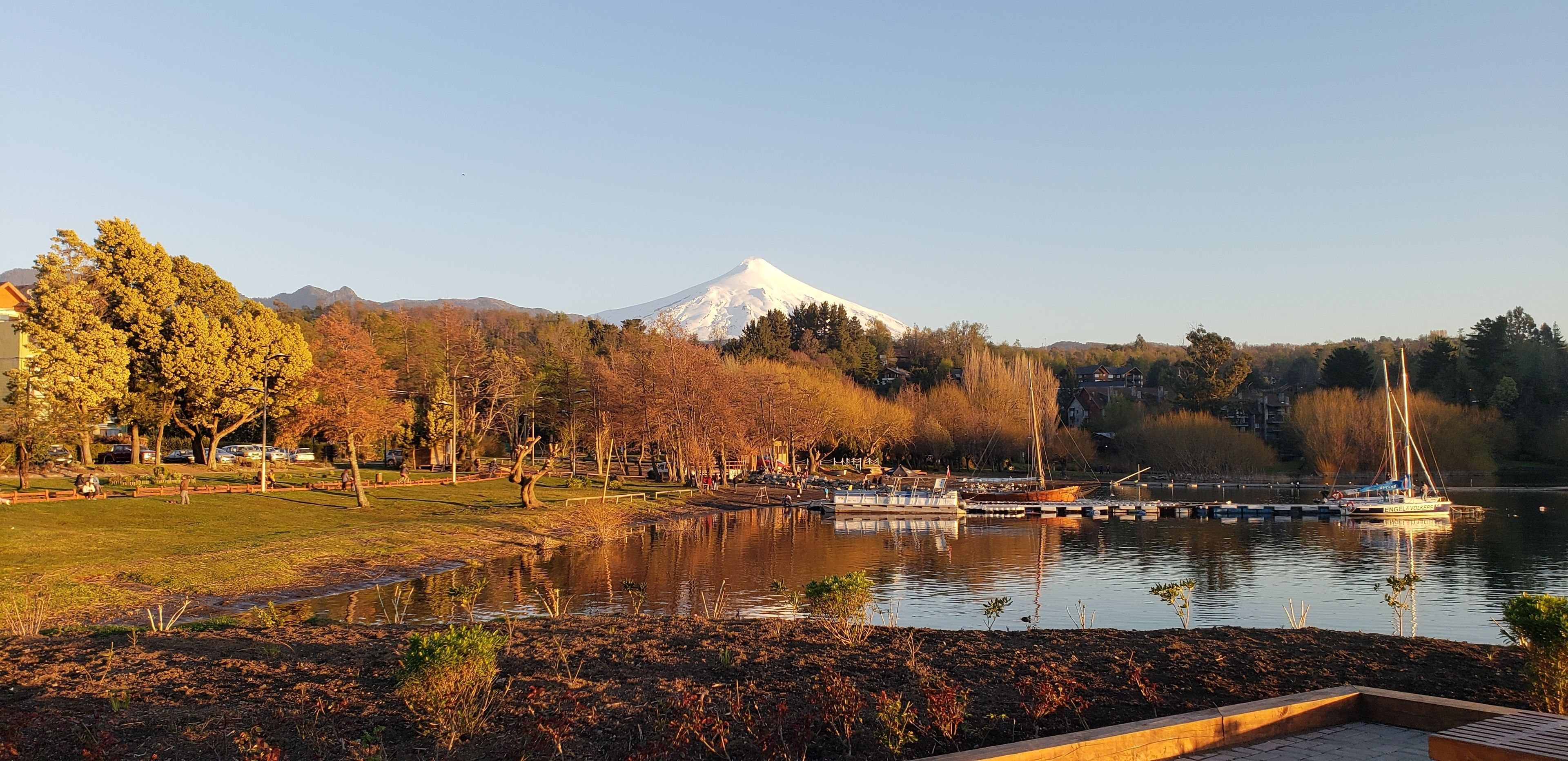 A park with a lake, boats, and a mountain in the background.