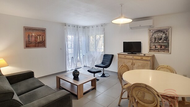 A living room with a sofa, a coffee table, a TV, a dining table with chairs, and a cabinet. - Cozy F2 Apartment, A/C, Terrace, Near Thermes & Park, Pet-Friendly, Lamalou-les-Bains (Lamalou-les-Bains)