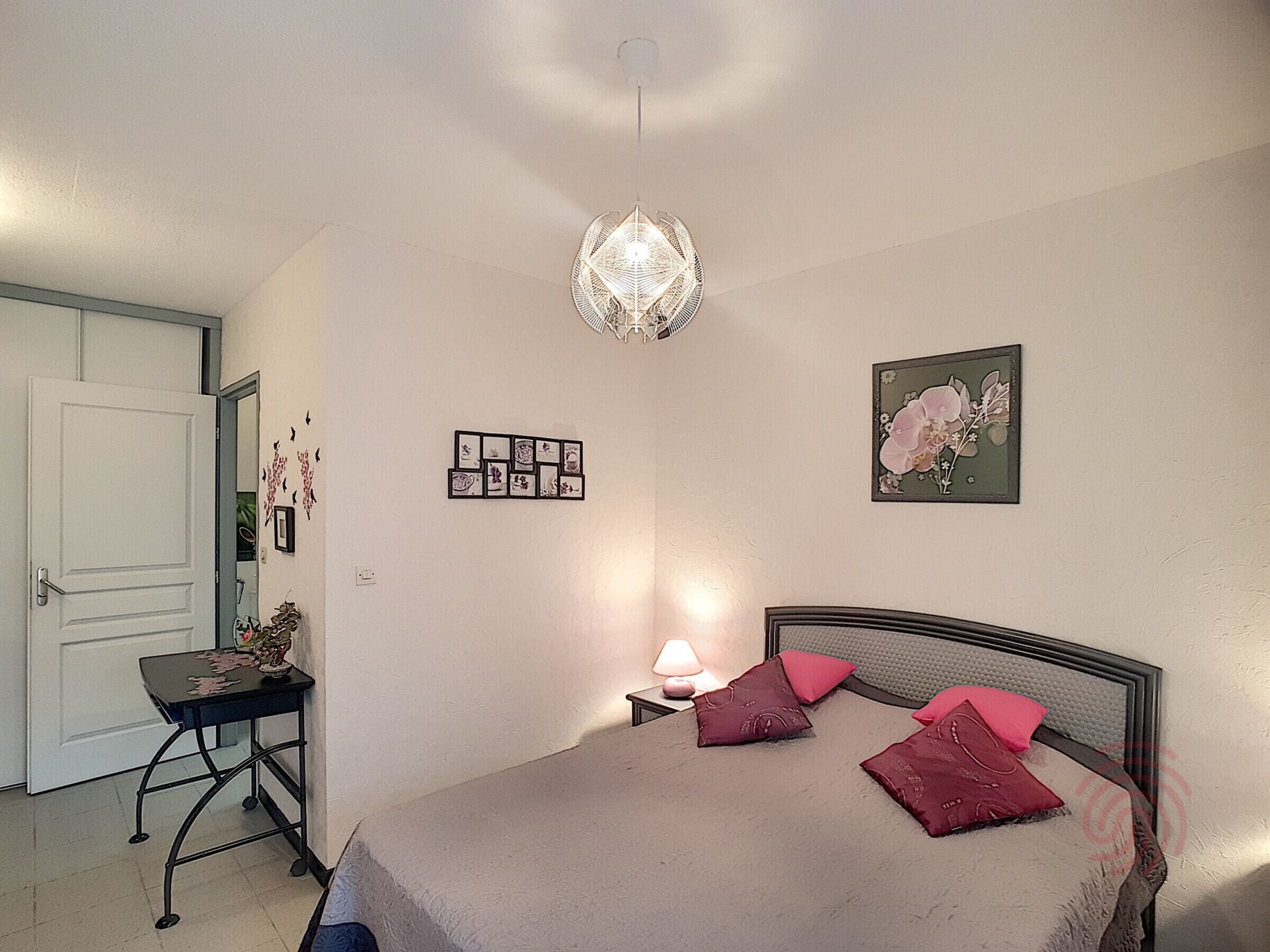 Un dormitorio con cama, escritorio, silla, lámpara y adornos en la pared.