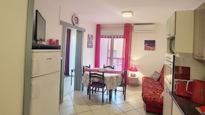 Cocina compacta con comedor, refrigerador, microondas y una pequeña mesa con sillas.