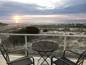 A balcony with a table and chairs overlooking a beach at sunset. - Best Beachfront - Expansive OCEAN VIEWS Perfect location! 2 decks & large patio (Ocean City)