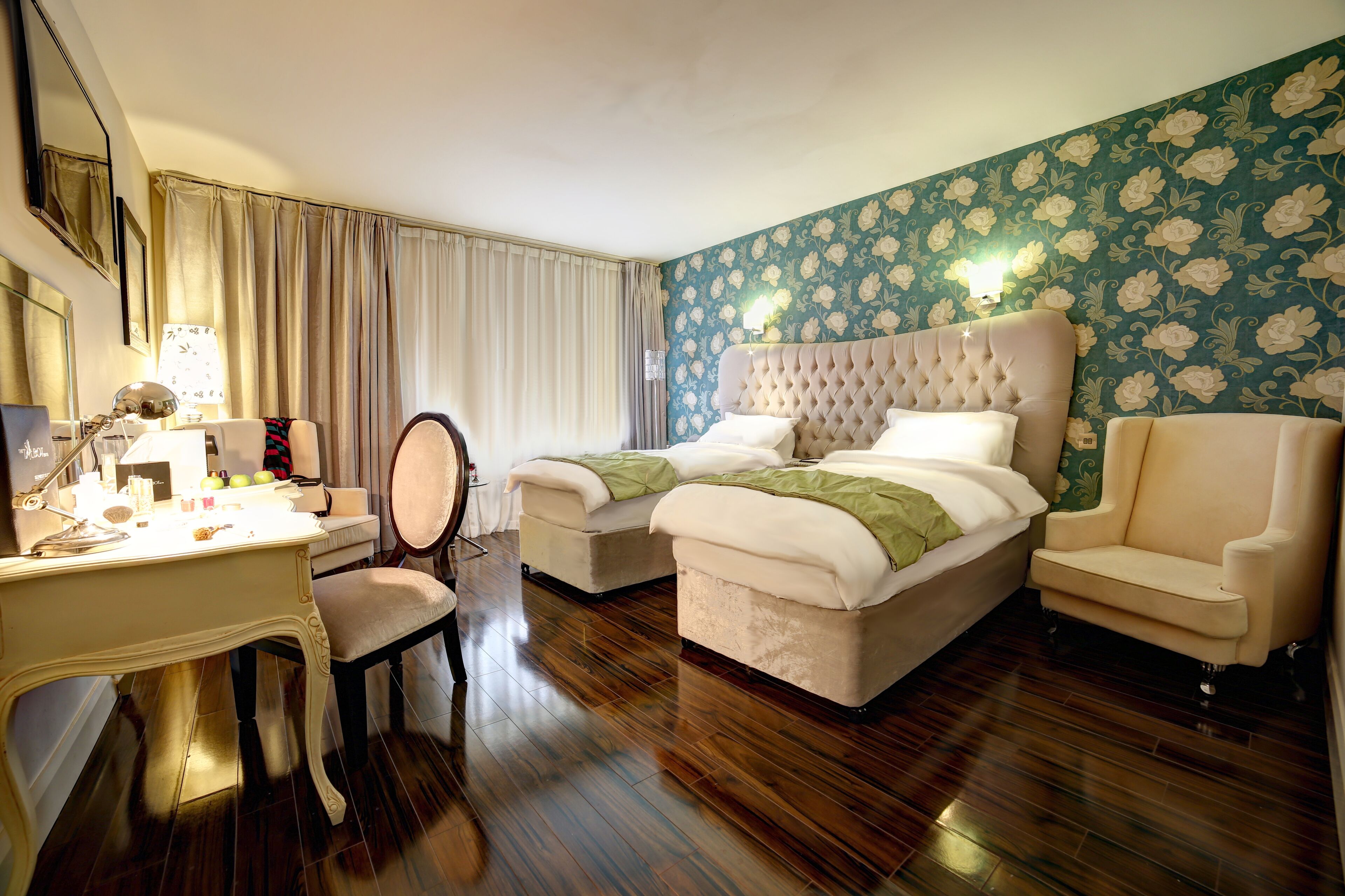 A hotel room with a large bed, a desk with a lamp, a chair, and a vanity.