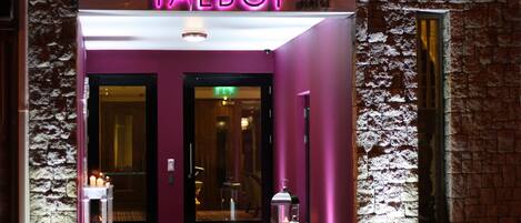 The entrance of a hotel with a neon sign reading "TALBOT".